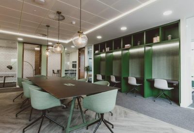 Modern coworking space with a dark wood table and green acoustic booths.