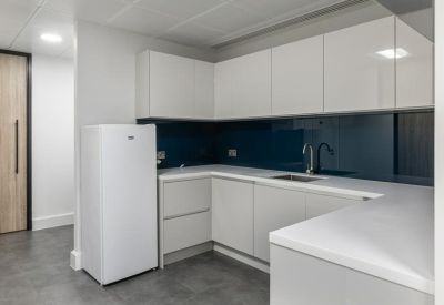 Contemporary kitchen with white cabinetry, dark blue backsplash, and integrated fridge.