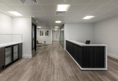 Modern reception area with a dark slatted desk and light wood flooring.