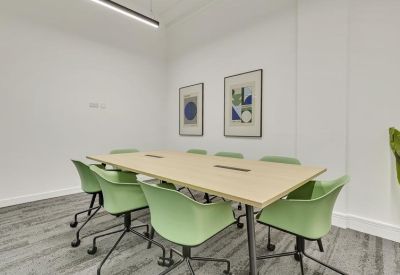 Private meeting room with a light wood table, pale green chairs, and abstract wall art.