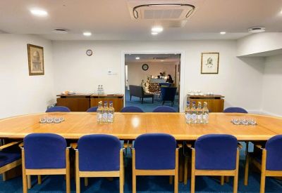 Professional boardroom with a long wooden table and blue upholstered chairs.