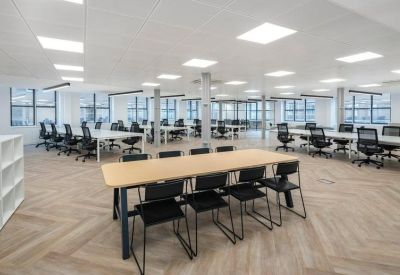 Spacious open-plan workspace with a large communal table and rows of modern desks.