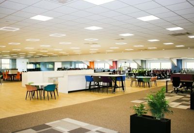 Expansive open-plan office floor with rows of desks and ergonomic chairs.