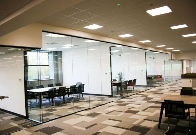 Glass-walled meeting room with a long table and black chairs.