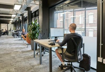Open-plan workspace with glass partitions and indoor plants.