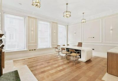Professional meeting area with a modern white conference table, chairs, and classic wall paneling.