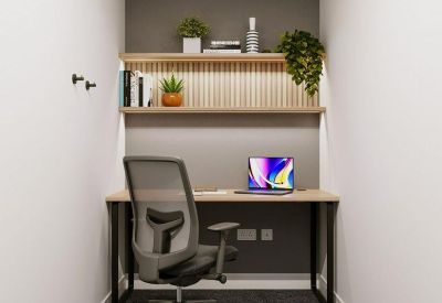 Compact private office nook with a desk, ergonomic chair, and shelving.