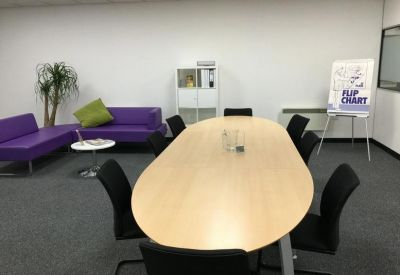 Spacious breakout area featuring purple sofas and a long oval meeting table.