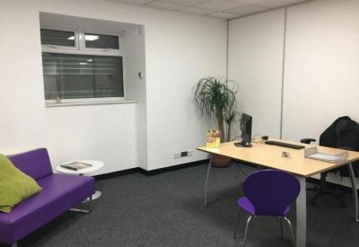 Private office suite with a purple sofa, desk setup, and indoor plant.