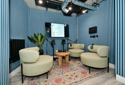 Podcast studio with blue striped walls, comfortable armchairs, and microphones.