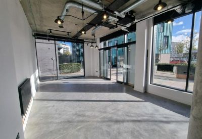 Spacious open-plan industrial office with concrete floors and large glass doors.