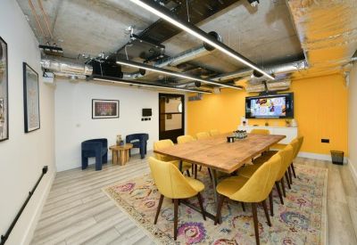 Vibrant meeting room with a large wooden table, yellow chairs, and a feature yellow wall.