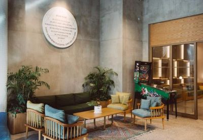 Lobby seating area with a circular wall plaque, pinball machine, and potted plants.