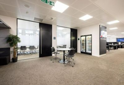 Lounge area with a round white table, black chairs, and a tall potted plant.