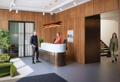 Modern reception area with wood-paneled walls, white desk, and green armchairs.