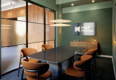 Intimate meeting room with a dark table, orange chairs, and green textured wall.