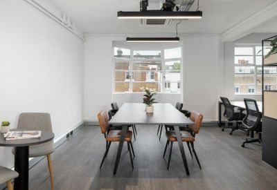Long communal dining or meeting table with mixed chairs and modern lighting.