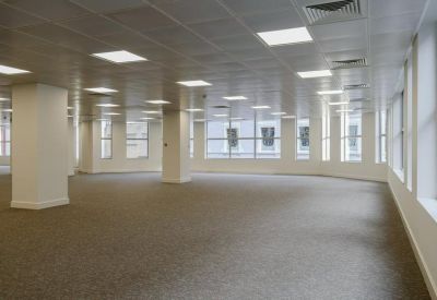 Spacious, empty open-plan floor with white pillars and grid ceiling.
