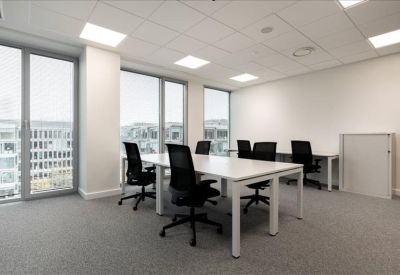 Bright four-person private office with white desks and black mesh chairs.