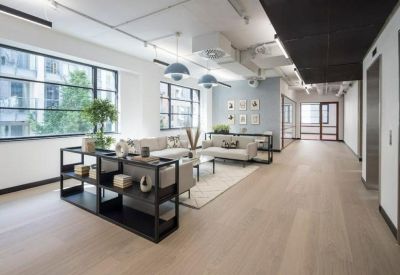 Bright breakout area with low-slung armchairs, wooden flooring, and modern pendant lighting.