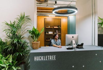 Reception desk with the Huckletree logo and lush green indoor plants.
