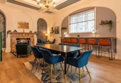 Spacious communal lounge with a marble fireplace, dining table, and window-side breakfast bar.