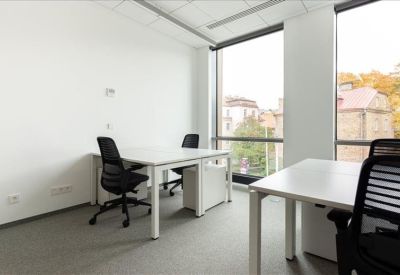 Bright two-person private office suite with large windows and minimalist white desks.