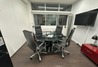 Waiting area with comfortable beige armchairs, a large plant, and warm wood-style flooring.