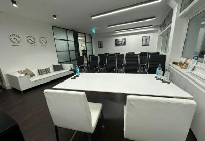 Elegant boardroom with a white table, black leather chairs, and framed artwork on the wall.