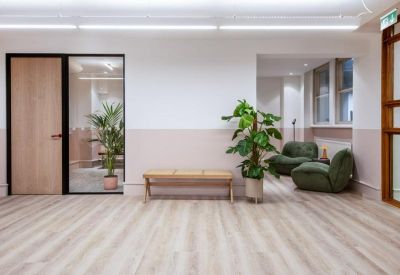 Reception lounge with green armchairs and a minimalist wooden bench.