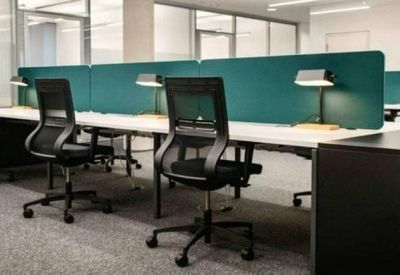 Modern open-plan workspace with black mesh chairs, white desks, and teal privacy screens.