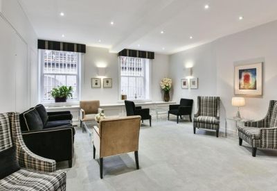 Lounge area featuring patterned armchairs, velvet sofas, and framed wall art.