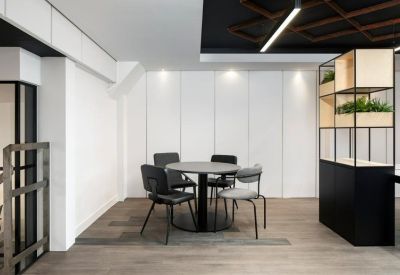 Informal meeting area with a round black table and gray upholstered chairs.