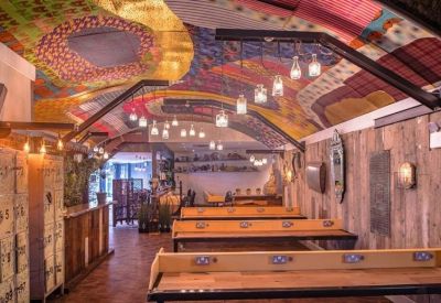 Coworking space featuring wooden long desks and a vibrant, multi-colored patterned ceiling.