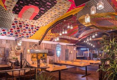 Spacious communal area with long work tables and an artistic, colorful vaulted ceiling.