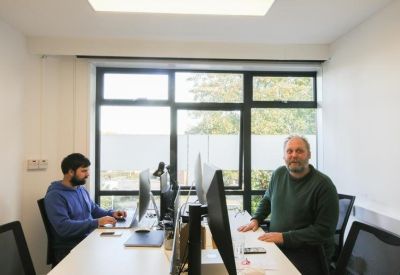 Two people working at a shared white desk in a bright office space.
