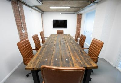 Boardroom with a long reclaimed wood table and tan leather chairs.