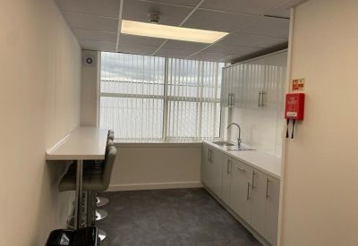 Bright communal kitchen area with breakfast bar seating and large window.