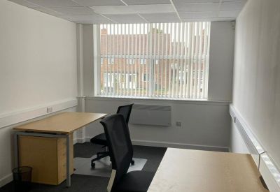 Internal two-person office suite with desks and large window.