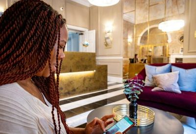 A person using a smartphone in a sophisticated lounge featuring a velvet sofa and gold accents.