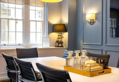 Executive meeting room with a large white table, leather chairs, and elegant wall sconces.