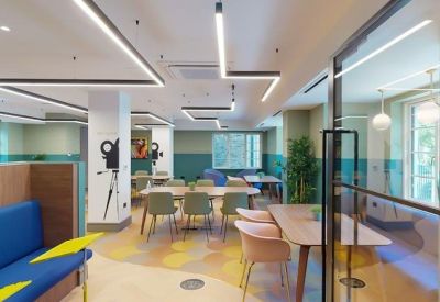 Colorful communal lounge with blue sofas, modern art, and zig-zag strip lighting at 49, Oxford Road, Finsbury Park.
