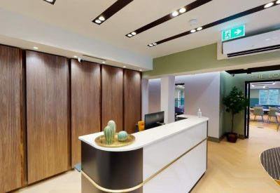 Bright reception area featuring a white curved desk, wood-paneled walls, and a potted plant.