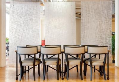 Bright dining area with wooden table and modern chairs set against decorative white privacy screens.