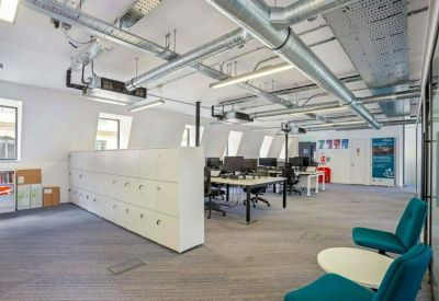 Industrial style open-plan office with exposed ductwork and white storage lockers.
