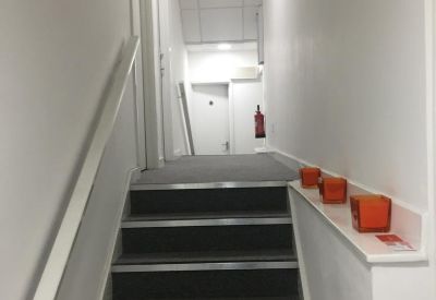 Brightly lit staircase with a white handrail leading to upper floor offices.