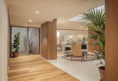 Lounge area with wooden flooring, glass partitions, and indoor plants.
