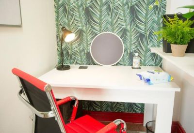 Single workstation with a vibrant red chair and leafy green feature wall.