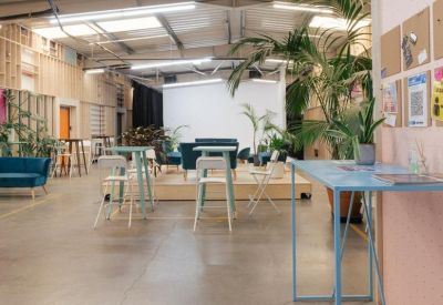 Large open floor space with light blue high-top tables and a reception desk in the distance.