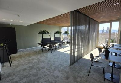 Spacious communal lounge with diverse seating areas, wooden ceilings, and a mesh room divider.